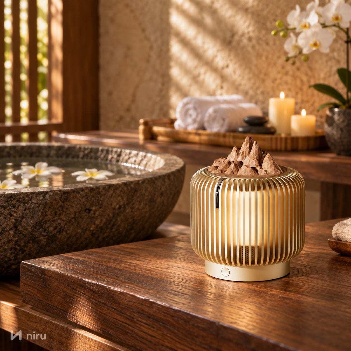 Difuzor de arome NIRU LumoAroma într-o cameră de spa zen, lângă un bazin de piatră cu flori